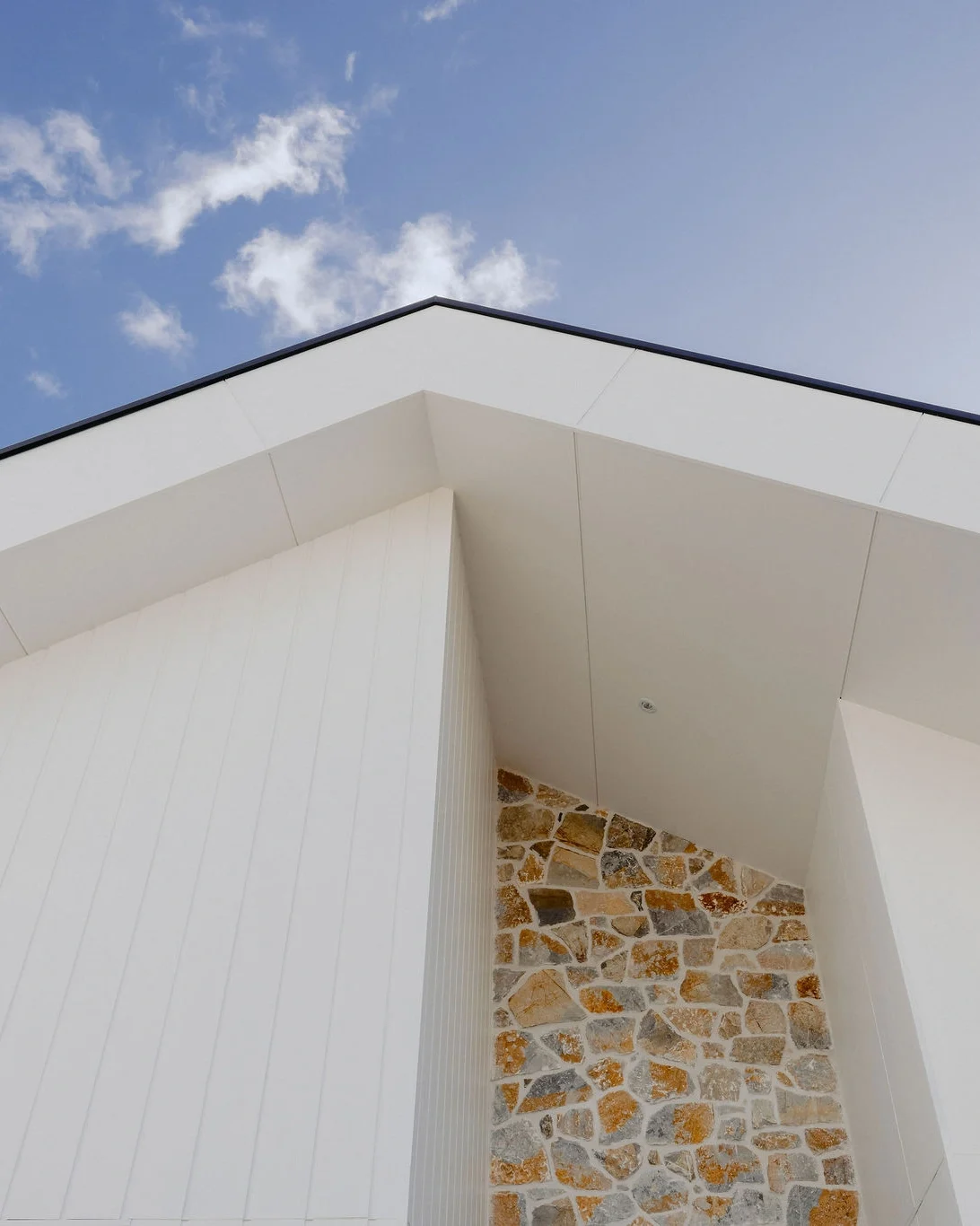 Modern coastal home exterior featuring clean white cladding and natural stone accent wall, designed and built by Indianic Homes in South West Western Australia