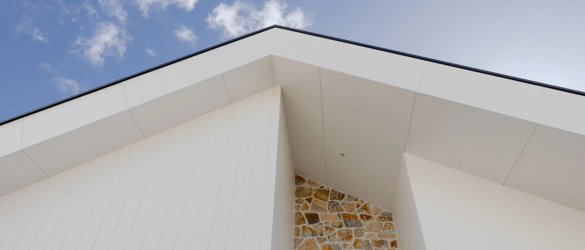 Modern coastal home exterior featuring clean white cladding and natural stone accent wall, designed and built by Indianic Homes in South West Western Australia